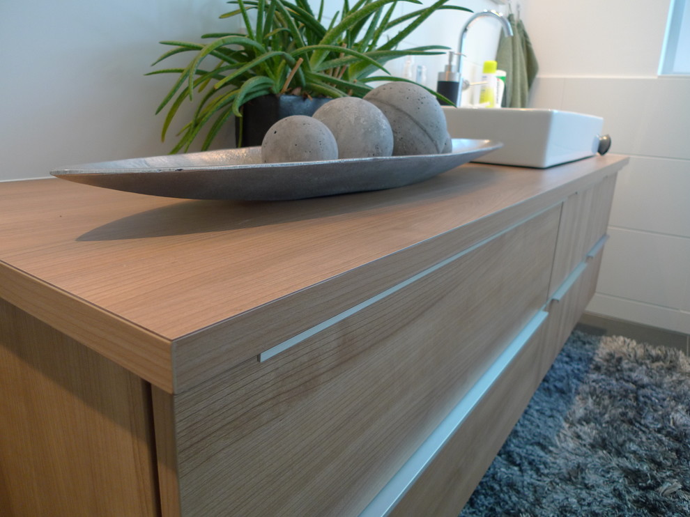 Example of a small minimalist master home design design with medium tone wood cabinets and laminate countertops