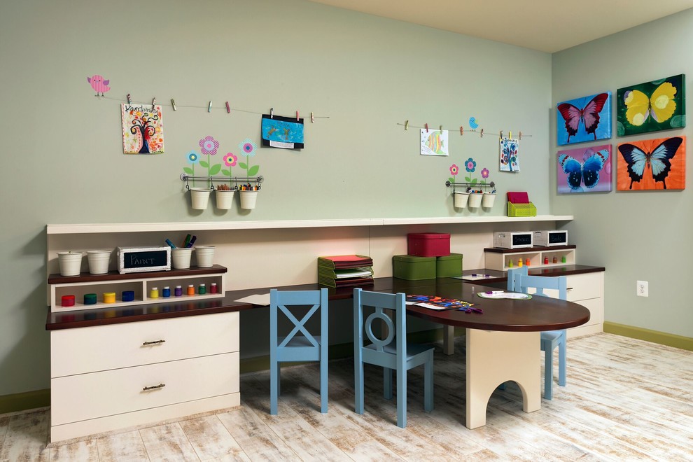 Creative and Unique Playroom - A perfect playroom space for two young girls to grow into.  The space contains a custom made playhouse, complete with hidden trap door, custom built in benches with plenty of toy storage and bench cushions for reading, lounging or play pretend.  In order to mimic an outdoor space, we added an indoor swing.  The side of the playhouse has a small soft area with green carpeting to mimic grass, and a small picket fence.  The tree wall stickers add to the theme.  A huge highlight to the space is the custom designed, custom built craft table with plenty of storage for all kinds of craft supplies.  The rustic laminate wood flooring adds to the cottage theme.
Bob Narod Photography