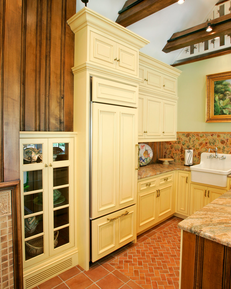 This is an example of a small traditional u-shaped open plan kitchen in Philadelphia with a farmhouse sink, granite benchtops, multi-coloured splashback, panelled appliances and terra-cotta floors.