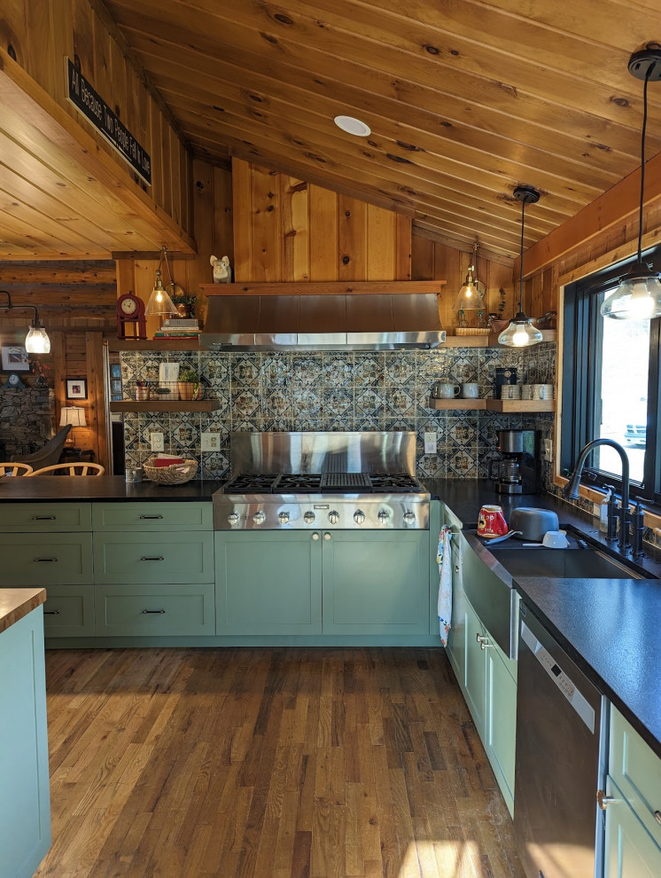 Eat-in kitchen - mid-sized rustic l-shaped medium tone wood floor, brown floor and vaulted ceiling eat-in kitchen idea with a farmhouse sink, shaker cabinets, green cabinets, granite countertops, multicolored backsplash, ceramic backsplash, stainless steel appliances, a peninsula and black countertops