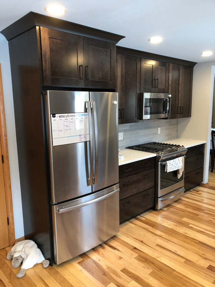Inspiration for a mid-sized transitional galley light wood floor and brown floor eat-in kitchen remodel with an undermount sink, shaker cabinets, black cabinets, quartz countertops, gray backsplash, subway tile backsplash, stainless steel appliances, no island and white countertops
