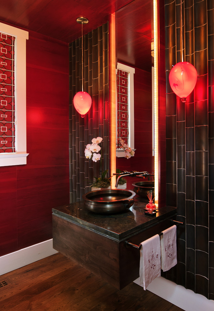 This is an example of an asian powder room in Salt Lake City with dark wood cabinets, red walls, medium hardwood floors and a vessel sink.