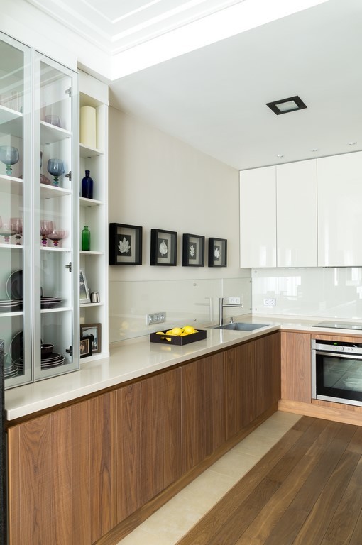 Photo of a contemporary l-shaped kitchen in Moscow with an undermount sink, flat-panel cabinets, medium wood cabinets, white splashback, glass sheet splashback and stainless steel appliances.
