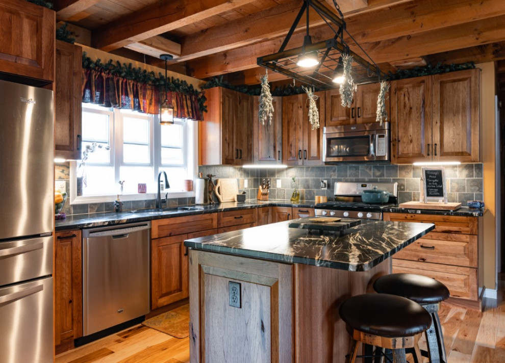 Kitchen - rustic l-shaped medium tone wood floor kitchen idea in Boston with an undermount sink, raised-panel cabinets, medium tone wood cabinets, granite countertops, gray backsplash, stainless steel appliances, an island and black countertops