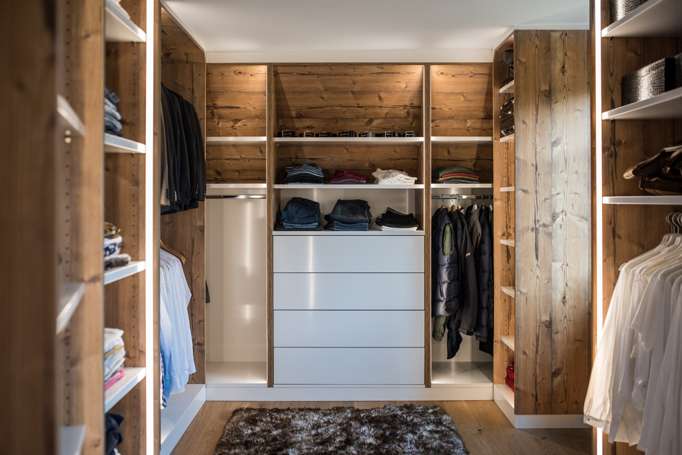 This is an example of a mid-sized country men's walk-in wardrobe in Stuttgart with open cabinets, medium wood cabinets, medium hardwood floors and brown floor.