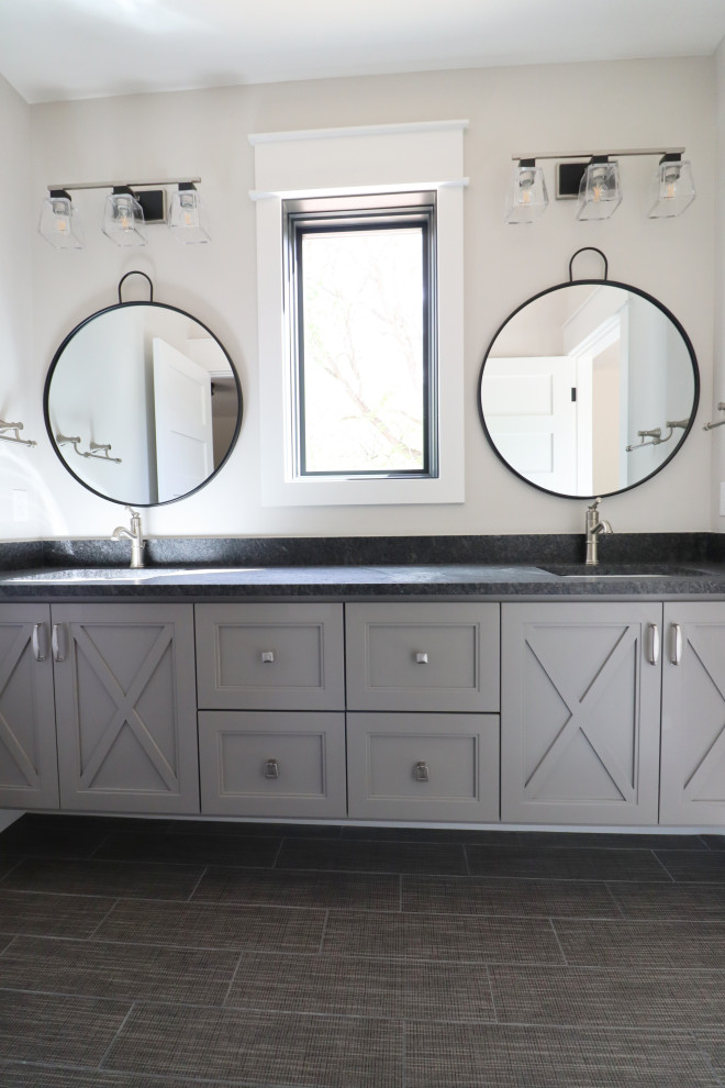 Photo of a traditional family bathroom in Omaha with freestanding cabinets, grey cabinets, an alcove bath, a shower/bath combination, a one-piece toilet, grey tiles, porcelain tiles, porcelain flooring, a submerged sink, granite worktops, a shower curtain, black worktops, an enclosed toilet, double sinks and a built in vanity unit.