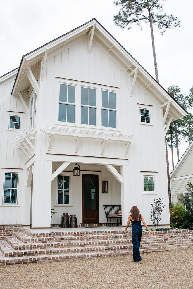 Photo of a mid-sized country two-storey white house exterior in Charleston with concrete fiberboard siding, a gable roof and a metal roof.