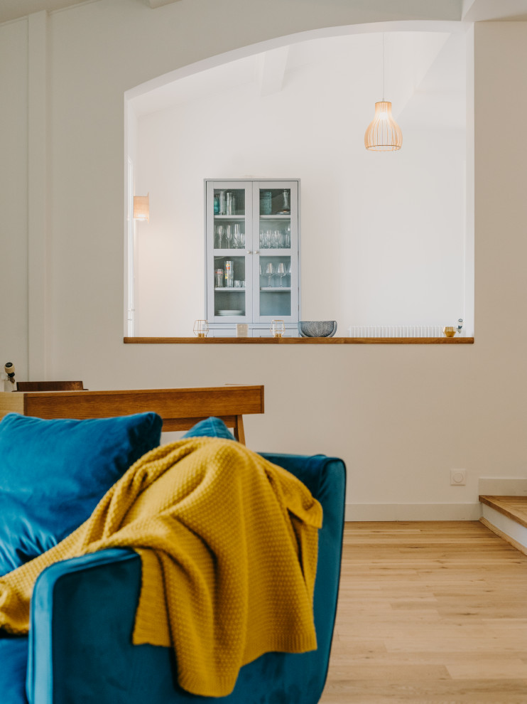 Foto de salón abierto grande con paredes azules, suelo de madera clara, estufa de leña, televisor colgado en la pared, suelo beige y vigas vistas