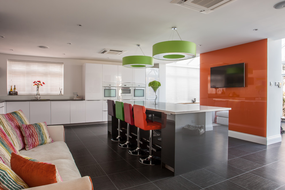 Photo of a large contemporary l-shaped open plan kitchen in Essex with an undermount sink, flat-panel cabinets, white cabinets, quartzite benchtops, orange splashback, glass sheet splashback, white appliances, porcelain floors and with island.