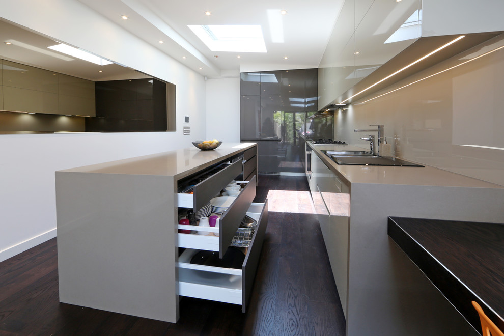Inspiration for a contemporary l-shaped eat-in kitchen in Melbourne with a drop-in sink, flat-panel cabinets, white cabinets, quartz benchtops, glass sheet splashback and stainless steel appliances.