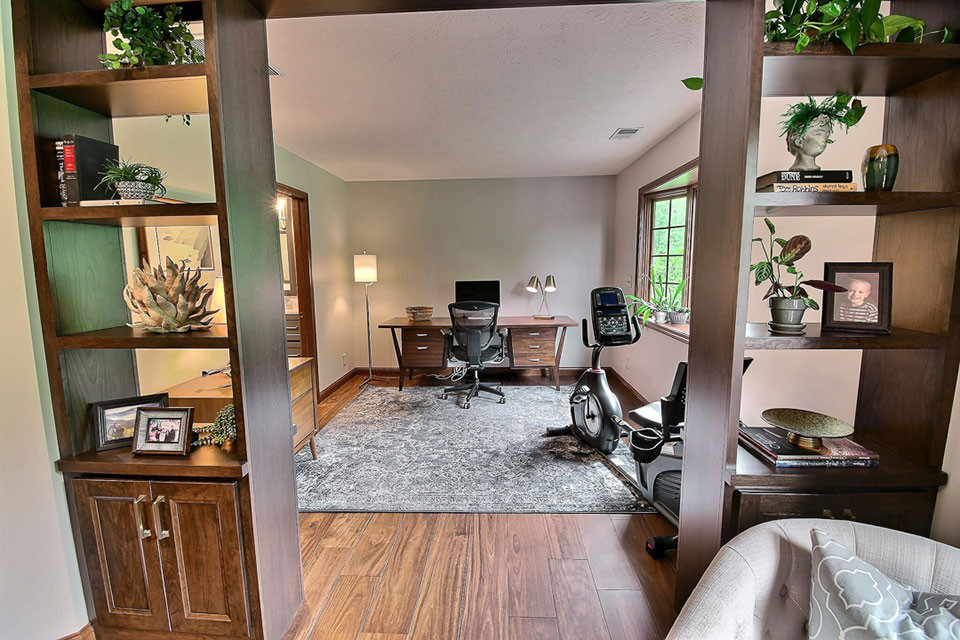 Bild på ett stort vintage arbetsrum, med mellanmörkt trägolv, ett fristående skrivbord, brunt golv, grå väggar och en dubbelsidig öppen spis