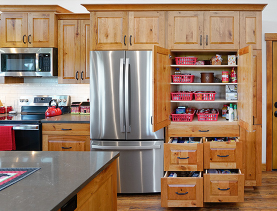 Kitchen - large rustic medium tone wood floor, brown floor and vaulted ceiling kitchen idea with a farmhouse sink, raised-panel cabinets, medium tone wood cabinets, concrete countertops, white backsplash, ceramic backsplash, stainless steel appliances, an island and gray countertops