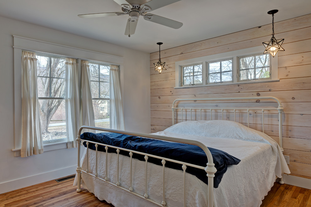 Photo of a mid-sized arts and crafts guest bedroom in New York with white walls, medium hardwood floors, no fireplace and brown floor.