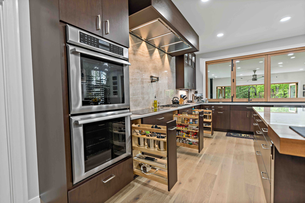 This is an example of a large contemporary u-shaped kitchen pantry in Dallas with a submerged sink, flat-panel cabinets, dark wood cabinets, quartz worktops, beige splashback, stone slab splashback, stainless steel appliances, light hardwood flooring, an island and beige worktops.