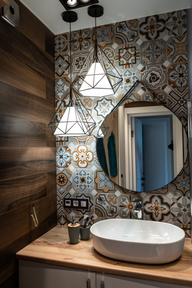Small contemporary powder room in Moscow with flat-panel cabinets, white cabinets, multi-coloured tile, mosaic tile, brown walls, a vessel sink, wood benchtops, beige benchtops and a built-in vanity.