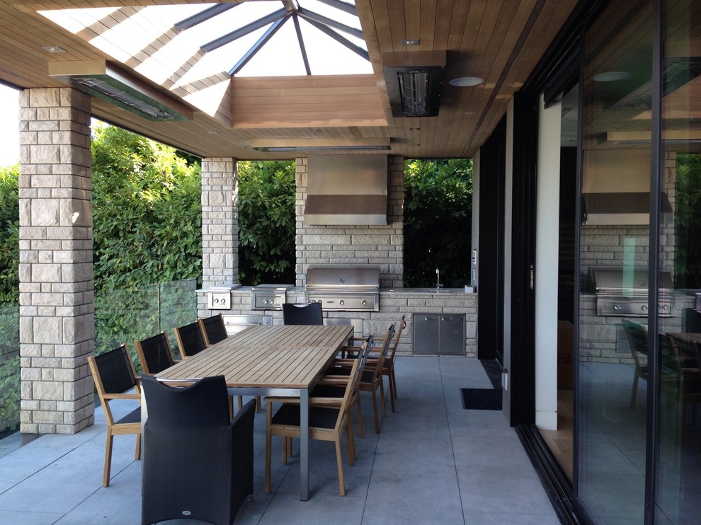 Large contemporary backyard patio in Vancouver with concrete pavers and a roof extension.