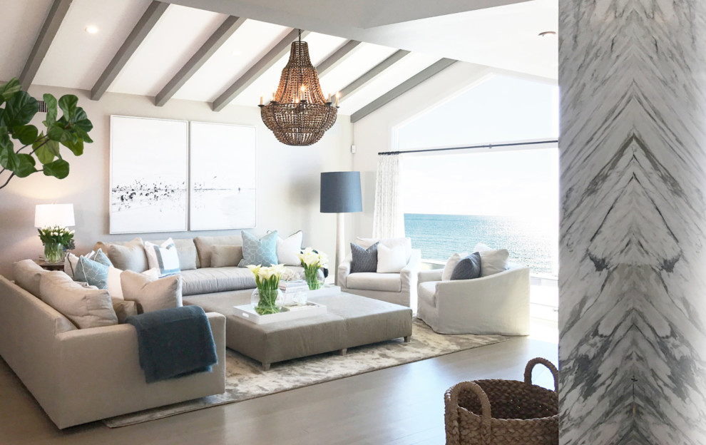 This is an example of a beach style open concept living room in Orange County with beige walls, medium hardwood floors, no tv and brown floor.