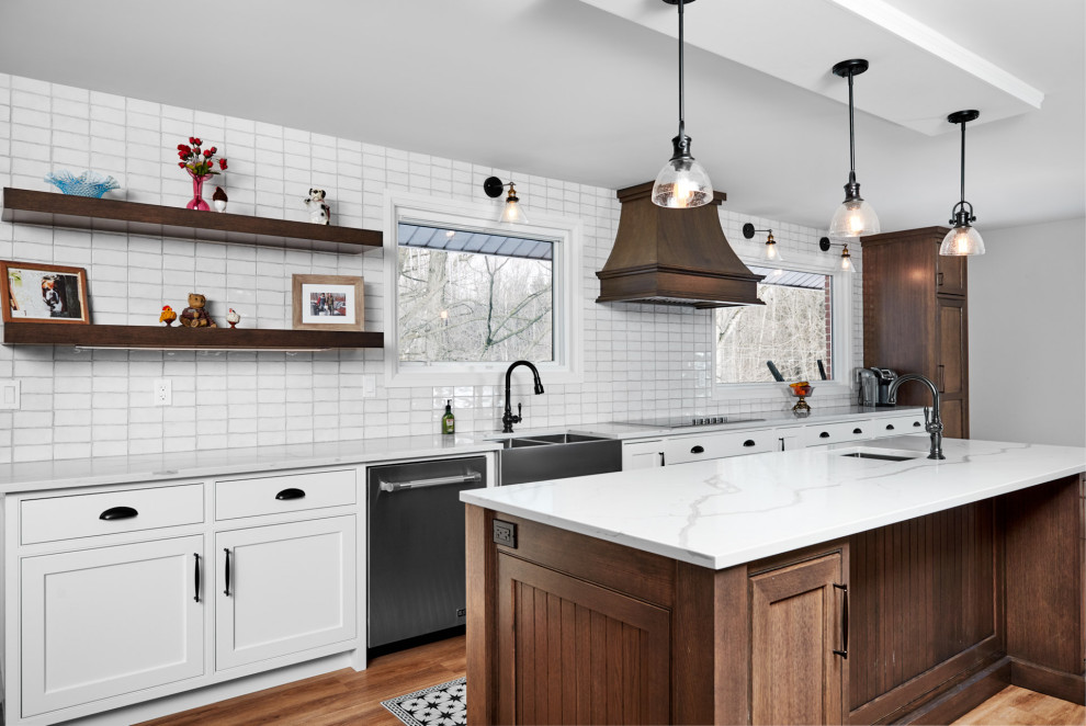 Example of a transitional galley light wood floor and brown floor enclosed kitchen design in Toronto with a farmhouse sink, shaker cabinets, white cabinets, quartzite countertops, white backsplash, subway tile backsplash, stainless steel appliances, an island and white countertops