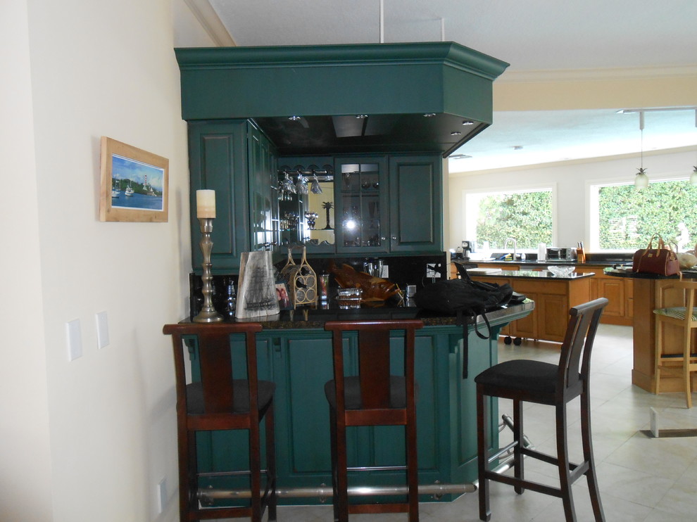 Large eclectic single-wall seated home bar in Tampa with a drop-in sink, raised-panel cabinets, green cabinets, granite benchtops, multi-coloured splashback and travertine floors.