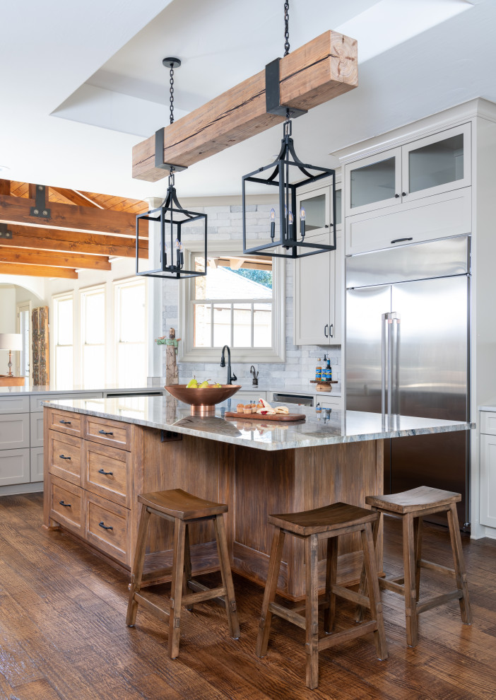 Inspiration for a large transitional dark wood floor, brown floor and exposed beam eat-in kitchen remodel with shaker cabinets, distressed cabinets, quartzite countertops, gray backsplash, ceramic backsplash, stainless steel appliances and an island