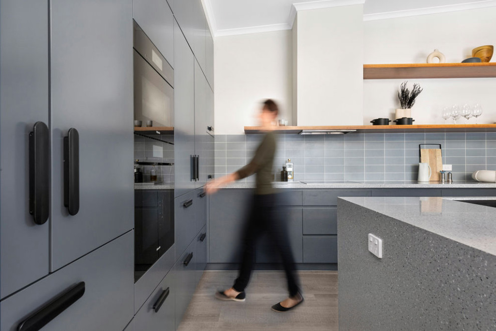 Design ideas for a mid-sized contemporary l-shaped kitchen pantry in Canberra - Queanbeyan with an undermount sink, flat-panel cabinets, blue cabinets, terrazzo benchtops, blue splashback, subway tile splashback, black appliances, laminate floors, with island, beige floor, blue benchtop and vaulted.