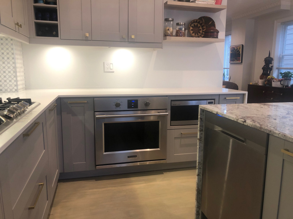 Mid-sized l-shaped eat-in kitchen in Toronto with an undermount sink, shaker cabinets, grey cabinets, quartz benchtops, marble splashback, stainless steel appliances, medium hardwood floors, with island, grey floor and white benchtop.