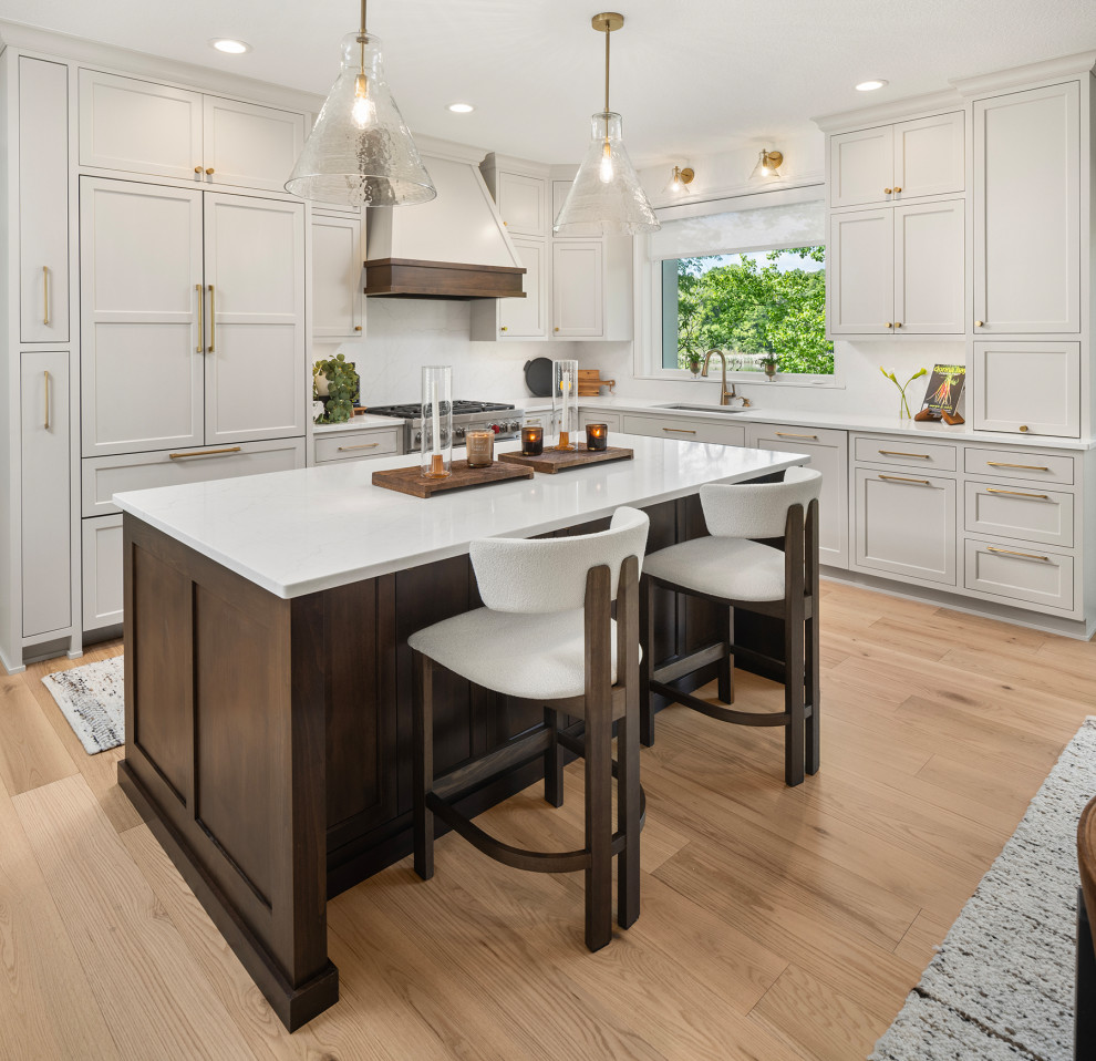 Inspiration for a mid-sized transitional u-shaped medium tone wood floor and brown floor eat-in kitchen remodel in Minneapolis with an undermount sink, recessed-panel cabinets, white cabinets, quartzite countertops, white backsplash, subway tile backsplash, paneled appliances, an island and white countertops
