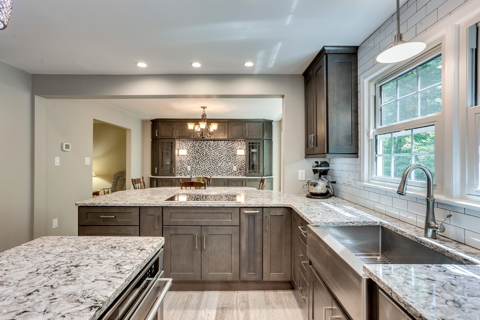 Inspiration for a large transitional u-shaped kitchen in DC Metro with a farmhouse sink, shaker cabinets, grey cabinets, quartz benchtops, white splashback, subway tile splashback, stainless steel appliances and with island.