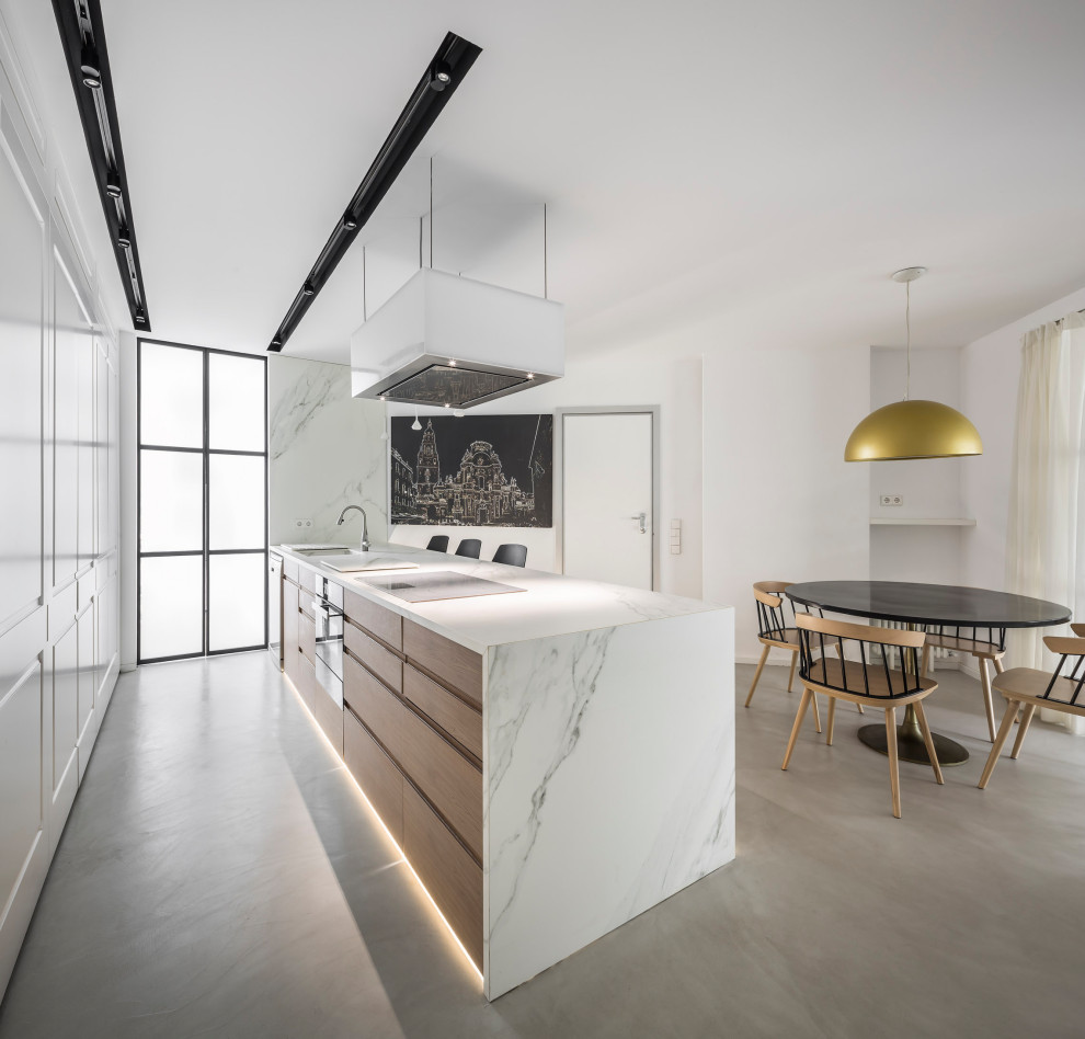 This is an example of a large contemporary single-wall separate kitchen in Valencia with an undermount sink, panelled appliances, concrete floors, with island, grey floor and white benchtop.