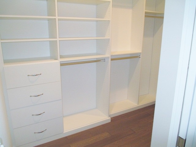 Inspiration for a small modern gender-neutral walk-in wardrobe in Los Angeles with medium hardwood floors, flat-panel cabinets, white cabinets and brown floor.