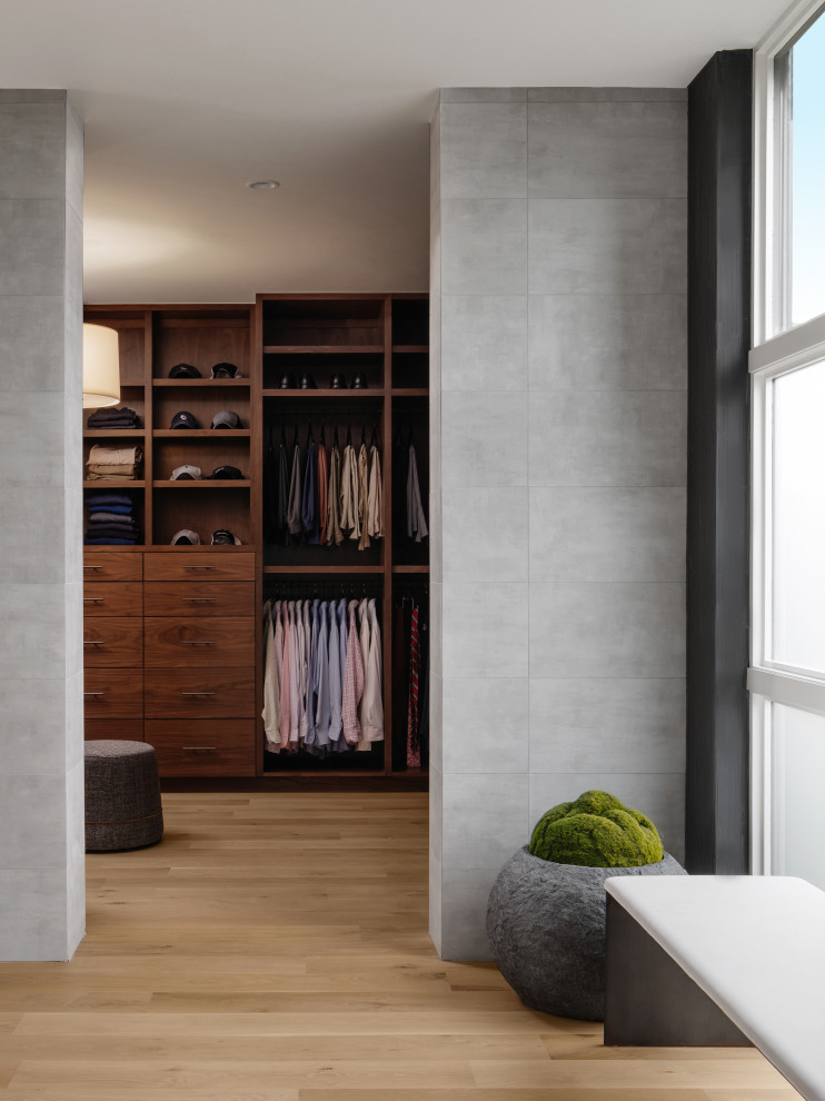 This is an example of a gender-neutral walk-in wardrobe in Austin with light hardwood floors, beige floor and dark wood cabinets.