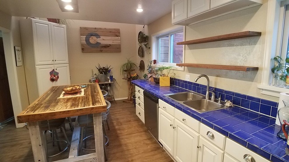Large mountain style l-shaped light wood floor and brown floor eat-in kitchen photo in Denver with a double-bowl sink, raised-panel cabinets, white cabinets, tile countertops, blue backsplash, ceramic backsplash, stainless steel appliances and an island