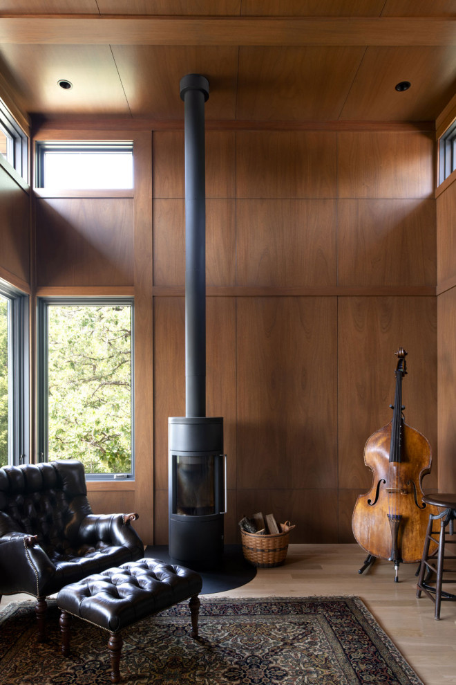 Immagine di uno studio moderno con libreria, pareti marroni, stufa a legna e pareti in legno