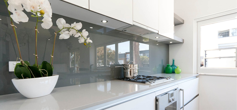 Inspiration for a contemporary galley eat-in kitchen in Sydney with beaded inset cabinets, white cabinets, quartz benchtops, grey splashback, glass sheet splashback, stainless steel appliances and with island.
