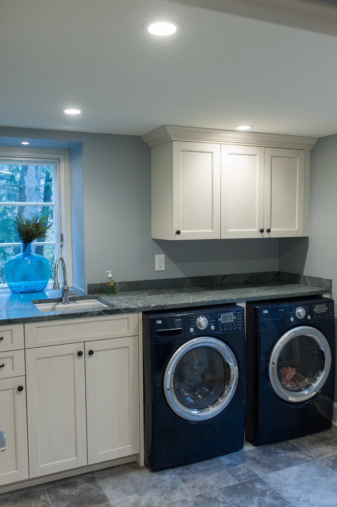 Photo of a traditional single-wall laundry room in Philadelphia with an undermount sink, white cabinets, soapstone benchtops and a side-by-side washer and dryer.