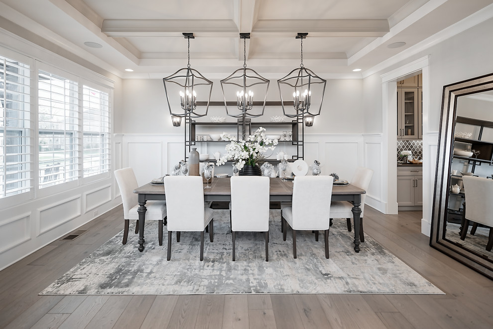 Large dining room in Charlotte with grey walls, light hardwood floors, coffered and decorative wall panelling.