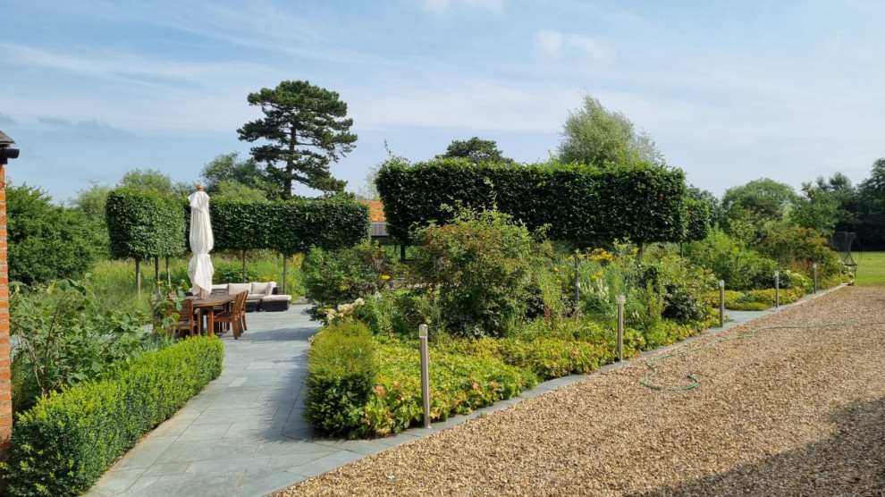Cette photo montre un très grand jardin à la française tendance avec un mur de soutènement et des pavés en pierre naturelle.