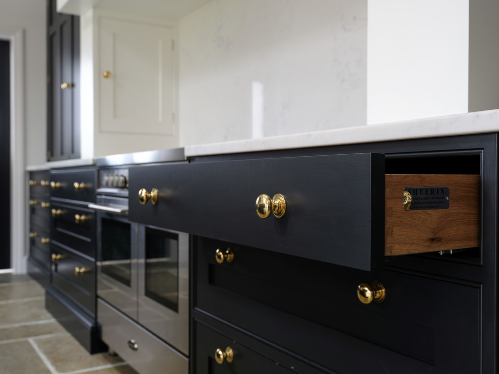 Design ideas for a traditional kitchen in Cheshire with a belfast sink, black cabinets, quartz worktops, an island and white worktops.