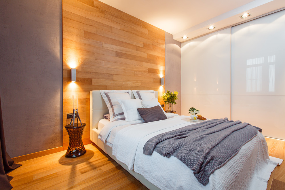 Contemporary bedroom in Other with grey walls and medium hardwood floors.
