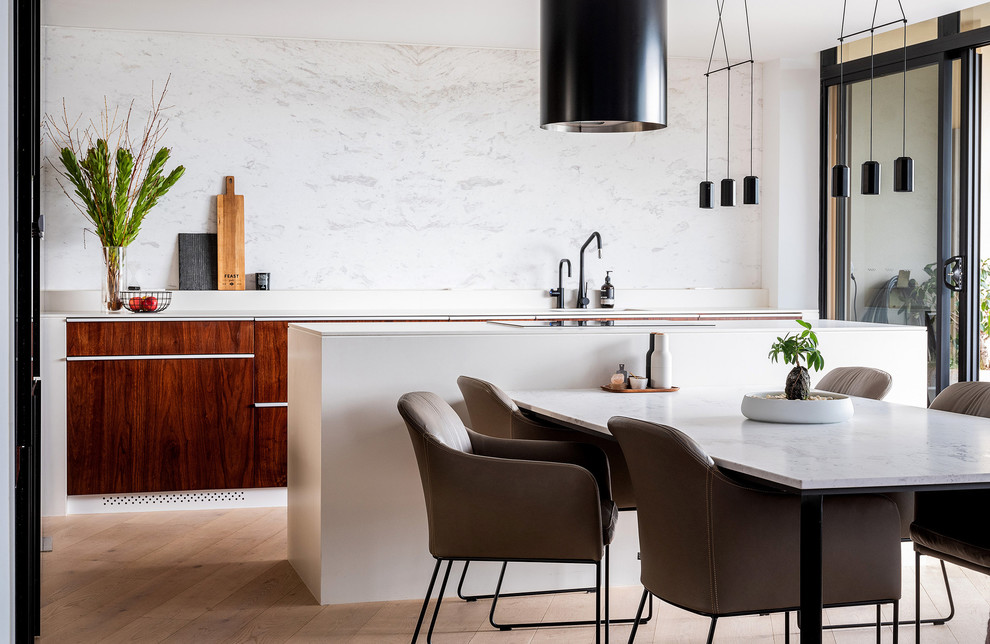 Design ideas for a small contemporary galley eat-in kitchen in Sydney with flat-panel cabinets, marble benchtops, white splashback, marble splashback, light hardwood floors, with island, white benchtop, dark wood cabinets and brown floor.