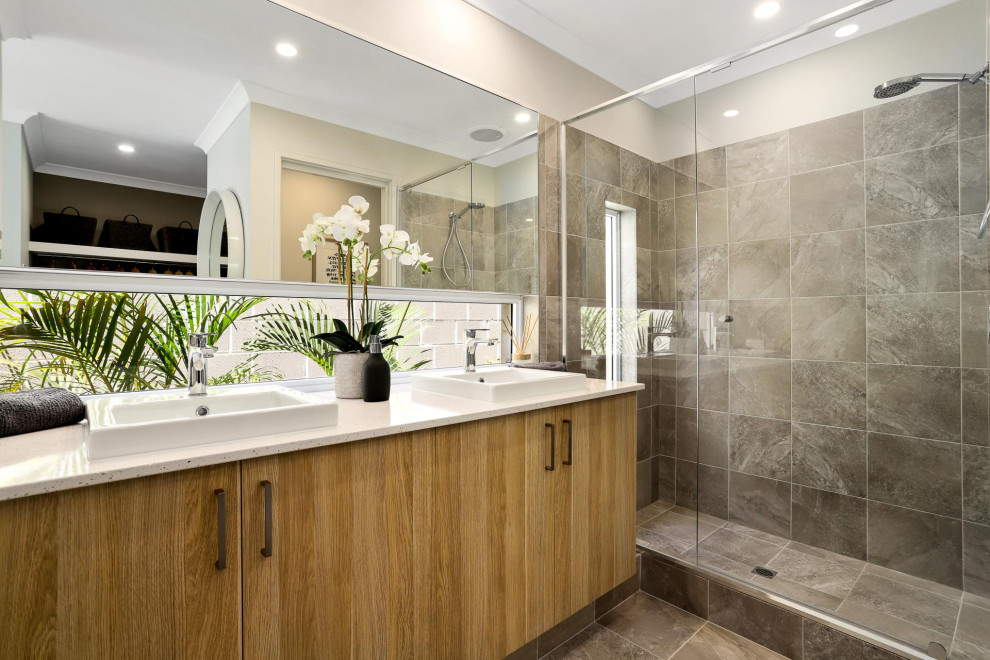 Photo of a large contemporary 3/4 bathroom in Perth with flat-panel cabinets, medium wood cabinets, an alcove shower, gray tile, porcelain tile, beige walls, porcelain floors, a vessel sink, grey floor, a sliding shower screen, white benchtops and a built-in vanity.