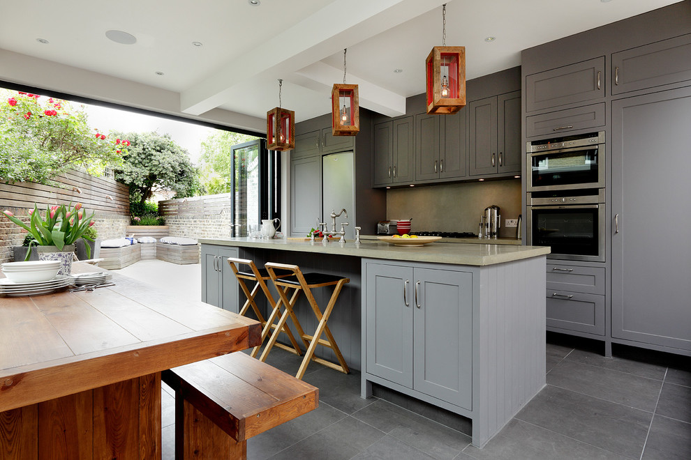 Photo of a transitional single-wall eat-in kitchen in London with shaker cabinets, grey cabinets, concrete benchtops, stainless steel appliances, porcelain floors and with island.