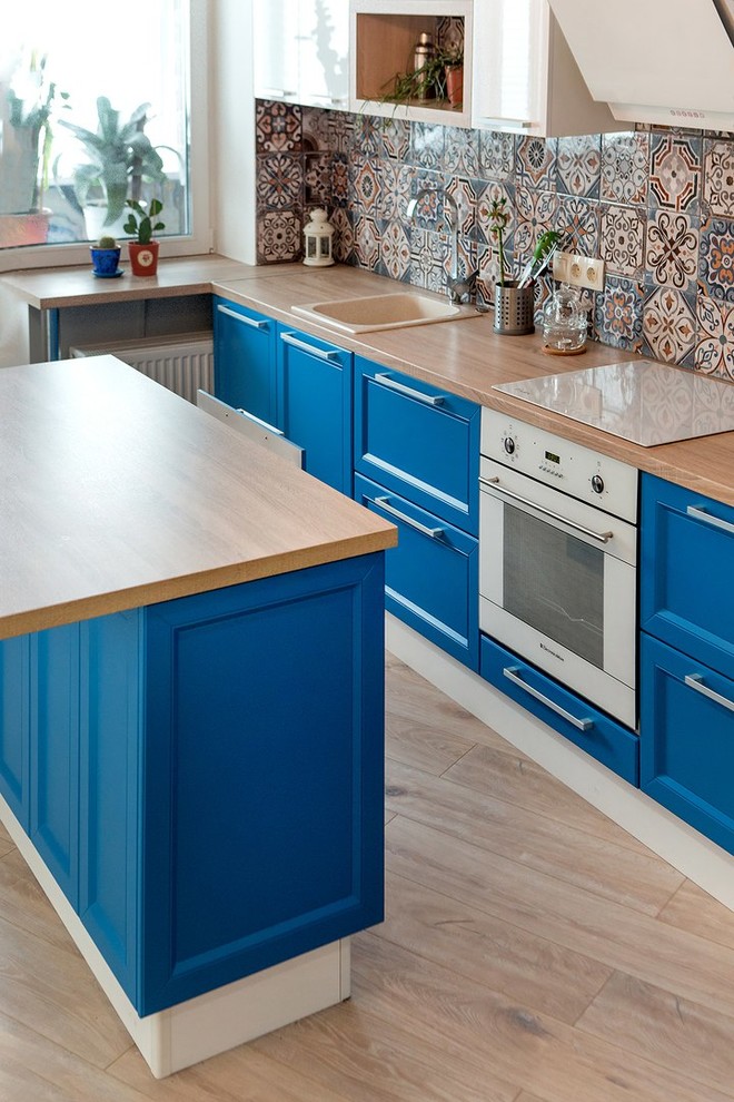 Inspiration for a mid-sized eclectic single-wall eat-in kitchen in Other with a drop-in sink, recessed-panel cabinets, blue cabinets, laminate benchtops, multi-coloured splashback, ceramic splashback, white appliances, laminate floors, with island and beige floor.