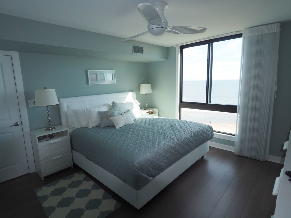 This is an example of a mid-sized beach style master bedroom in DC Metro with blue walls and dark hardwood floors.