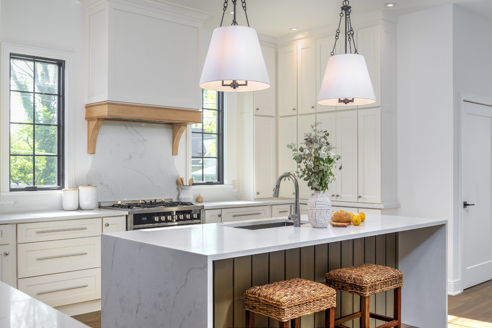 Open concept kitchen - mid-sized transitional u-shaped medium tone wood floor and brown floor open concept kitchen idea in Indianapolis with an undermount sink, shaker cabinets, white cabinets, quartz countertops, white backsplash, stainless steel appliances, an island and white countertops