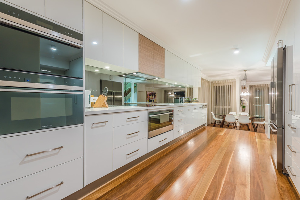 Contemporary eat-in kitchen in Perth with flat-panel cabinets, white cabinets, stainless steel appliances, medium hardwood floors and no island.