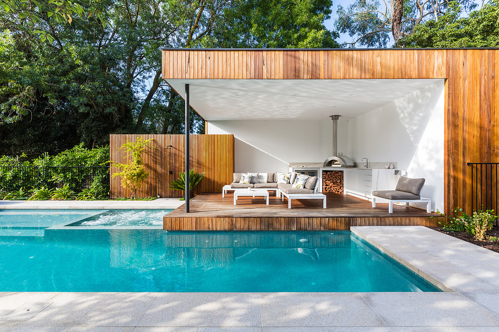 Photo of a contemporary backyard l-shaped lap pool in Melbourne with a hot tub and concrete pavers.