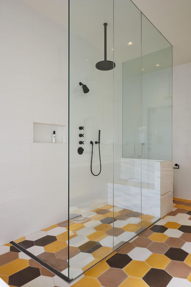 Design ideas for a large contemporary master bathroom in New York with a corner shower, white tile, porcelain tile, porcelain floors, multi-coloured floor, an open shower, flat-panel cabinets, light wood cabinets, a freestanding tub, white walls, an undermount sink, marble benchtops and white benchtops.