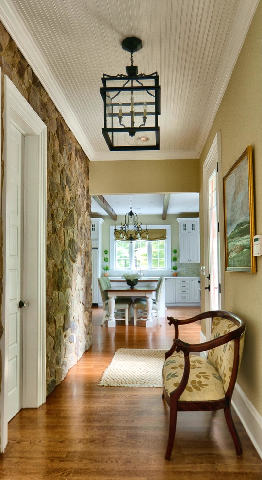 This is an example of a traditional hallway in DC Metro with beige walls, medium hardwood floors and brown floor.