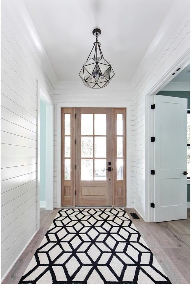 This is an example of a mid-sized country foyer in Charlotte with white walls, light hardwood floors, a light wood front door and beige floor.
